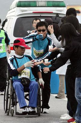 올해로 4회째를 맞은 서산간월도마라톤대회에 자원봉사자들이 참가한 장애인에게 물을 건네고 있다.