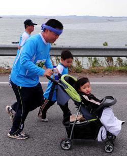 마라톤대회 한 참가자가 유모차를 끌고 자녀들과 함께 달리고 있다.