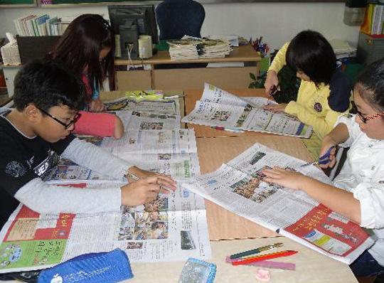 신문을 오려 환경신문을 만들고 있는 학생들.