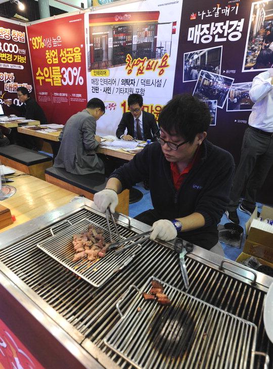 박람회에 참가한 한 프랜차이즈 업체 관계자가 방문객을 대상으로 시식행사를 열기 위해 고기를 굽고 있다.  빈운용 기자