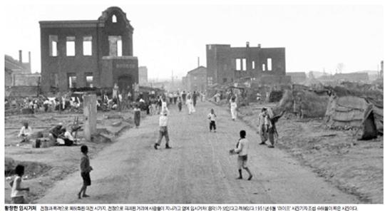 황량한 임시거처  전쟁과 폭격으로 폐허화된 대전 시가지. 전쟁으로 파괴된 거리에 사람들이 지나가고 옆에 임시거처(움막)가 보인다고 적혀있다.1951년 6월 `라이프` 사진기자 조셉 슈허첼이 찍은 사진이다.