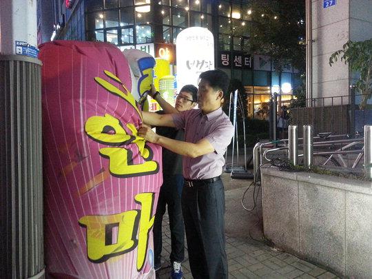둔산경찰서 생활질서계 곽정근(오른쪽) 계장과 안기현(왼쪽) 경장이 둔산1동의 한 학원 앞에 세워진 불법 풍선형 입간판을 정리하고 있다.