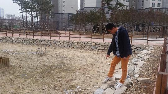 대전 트리풀시티 5블록에 거주하는 한 주민이 연지원 가장자리를 돌로 쌓아올린 엉성한 석축을 가리키고 있다.  원세연 기자
