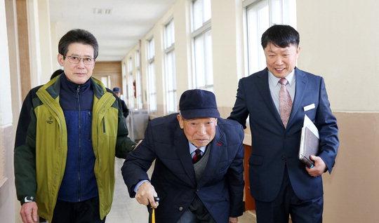 2일 서산시 부석중학교에서 김복환(81) 할아버지가 오경수(오른쪽) 교장과 아들의 도움을 받으며 입학식장으로 가고 있다.  사진=부석중학교 제공