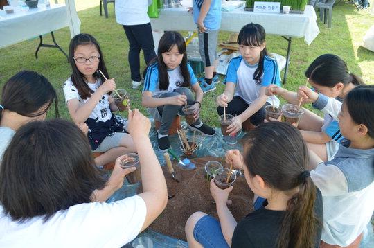 지난 20일 충남도청 잔디광장에서 열린 제8회 목재페스티벌 체험행사에 참여한 초등학생들이 벼화분을 만들고 있는 모습(위쪽)과  나무 명패를 만들고 있는 모습.  최정 기자