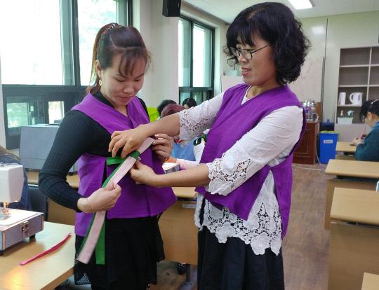 생활한복만들기 교육에서 김희자 강사가 장미향 회원에세 완성된 생활한복 배자조끼 옷고름 매는 법을 지도하고 있다. 사진=군 농업기술센터 제공
