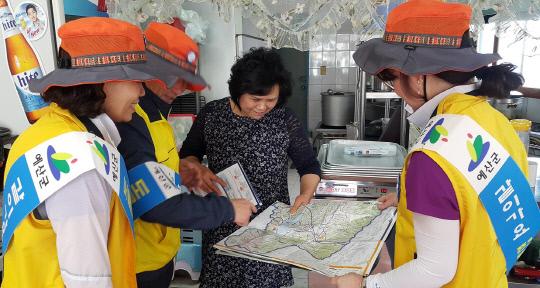 지난 15일 예산읍 천변로 일대에서 실시된 `도로명주소 홍보캠페인` 참가자들이 지도를 이용해 주민에게 도로명주소 사용 방법을 안내하고 있다. 사진=예산군 제공
