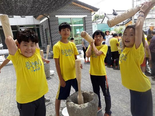 음성 원남초등학교 학생들이 삼성면 대실 비타민 마을에서 절구에 찹쌀을 넣고 찧고 있다. 사진=음성교육지원청 제공

