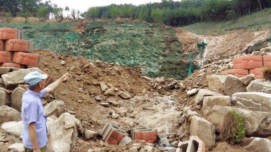 북면 용암리의 전원주택단지 개발현장의 옹벽과 산림절개지가 무너진 곳을 주민이 가리키고 있다. 사진=윤평호 기자
