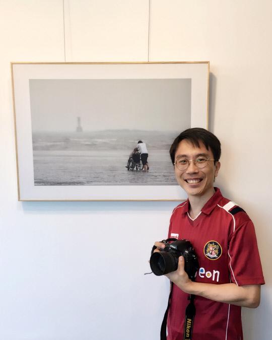허윤기 목사가 대전 유성구 노은동의 한 카페에서 상설전시하고 있는 자신의 사진작품 앞에서 카메라를 들고 환히 웃고 있다. 강은선 기자
