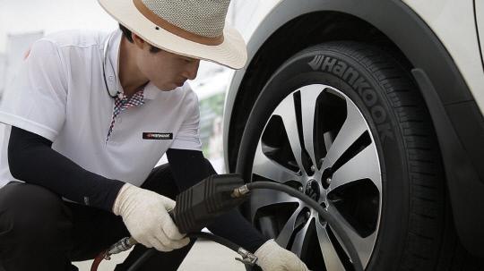 한국타이어 임직원이 하계 고속도로 안전점검 캠페인을 진행하며 고속도로 이용 차량의 타이어를 점검하고 있다. 사진=한국타이어 제공
