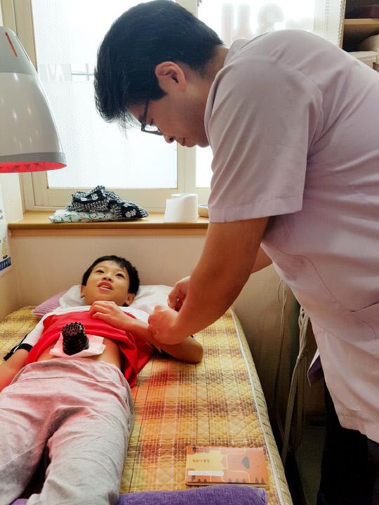 한방 호흡기질환 관리 프로그램의 일환으로 한의사가 아동에게 한방치료를 하고 있는 모습. 사진=서산시 제공
