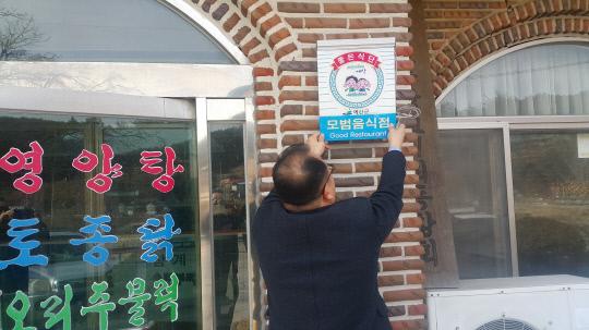 예산군 관계자가 지난 21일 모범음식점으로 선정된 한 식당에 모범음식점 표지판을 부착하고 있다. 사진=예산군 제공

