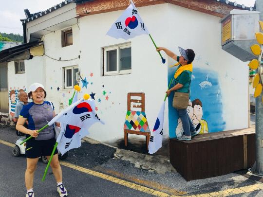 새마을 지도자 100여 명이 제천시 교동 민화마을을 찾아 가정에 국기대를 설치하고 태극기를 나눠줬다.사진=제천시 제공.
