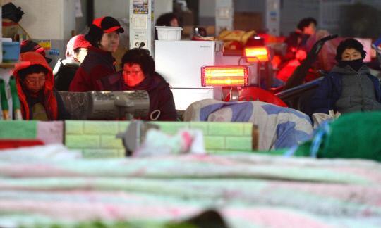 한파주의보가 내려진 24일 대전시 대덕구 오정동 농수산시장에서 새벽부터 나온 상인들이 작은 온열기에 의지해 추위를 견디고 있다.  사진=빈운용 기자