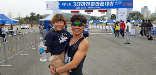 3대하천마라톤대회 10㎞코스 우승을 차지한 박창하(41)씨가 결승선 통과 후 아들과 함께 포즈를 취하고 있다. 사진 = 김대욱 기자 

