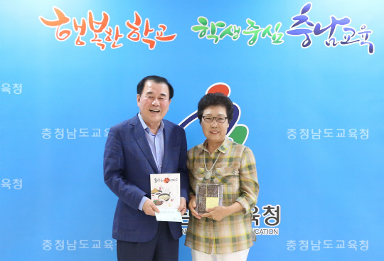 `요리는 감이여` 참가자를 대표해 김용선(사진 오른쪽) 할머니가 김지철 교육감에게 책을 전달하고 있다. 사진=충남도교육청 제공
