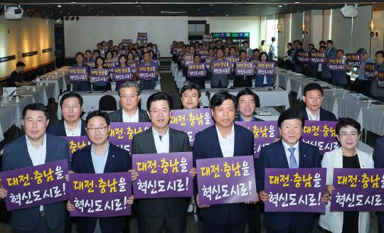 지난 7월 21일 열린 `대전시·자치구·더불어민주당 대전시당 확대 당정협의회` 당시 참석자들이 `대전·충남을 혁신도시로`라는 손팻말을 든 모습.  사진=대전시 제공