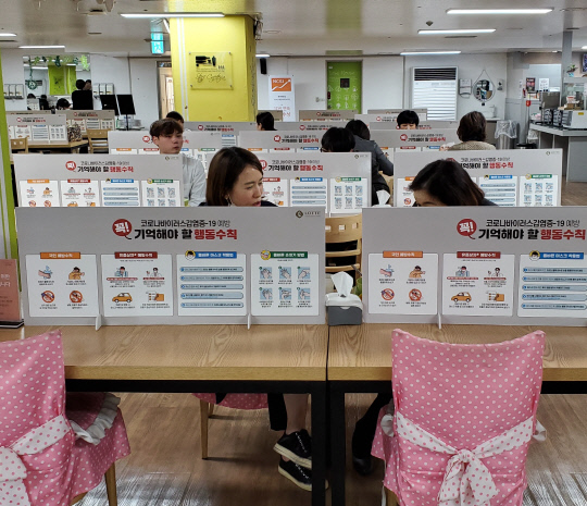 롯데백화점 대전점 직원들이 `사회적 거리두기 캠페인`을 위해 가림막이 설치된 직원식당에서 식사를 하고 있다.사진=롯데백화점 대전점
