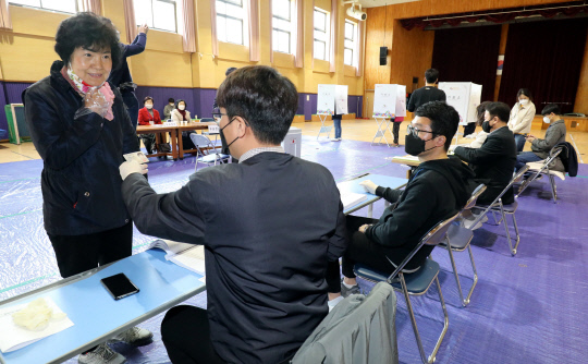 제21대 국회의원 선거일인 15일 대전월평초등학교에 마련된 월평1동 투표소에서 투표사무원이 유권자의 얼굴을 확인하고 있다.  빈운용 기자
