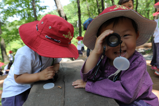 국립칠곡숲체원 토리유아숲체험원에서 아이들이 루페(휴대용 확대경)를 활용해 자연물을 관찰하고 있다. 사진=한국산림복지진흥원 제공 
