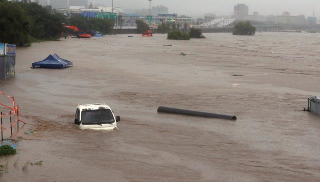 충청지역에 시간당 100mm 이상의 폭우가 쏟아진 30일 대전 갑천 원촌교 인근 공사현장에 세워진 트럭과 중장비들이 물이 잠겨 있다. 신호철 기자
