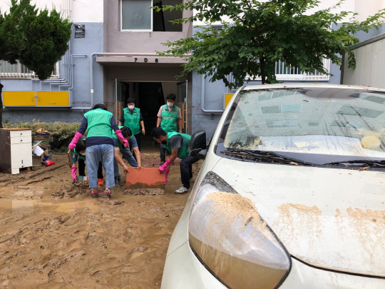 31일 자원봉사자들이 코스모스아파트 주차장에 쌓인 진흙더미를 치우고 있다. 사진=문승현 기자
