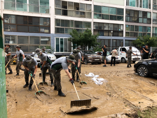31일 긴급동원된 군부대 인력들이 코스모스아파트 주차장 진흙더미를 걷어내고 있다. 사진=문승현 기자
