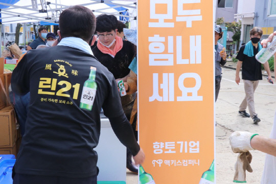 맥키스컴퍼니 임직원들이 대전 서구 코스모스아파트에서 수해복구에 구슬땀을 흘리는 자원봉사자 등에게 음료수 등을 나눠주고 있다. 사진=맥키스컴퍼니 제공

