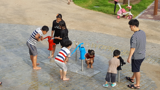 충청권을 강타하던 집중호우가 잠시 그친 5일 오후 5시 30분, 세종시 보람동 `땀범벅 놀이터`에서 어린이들이 수동식 펌프 놀이시설을 사용해 물놀이를 즐기고 있다. 사진=천재상 기자 
