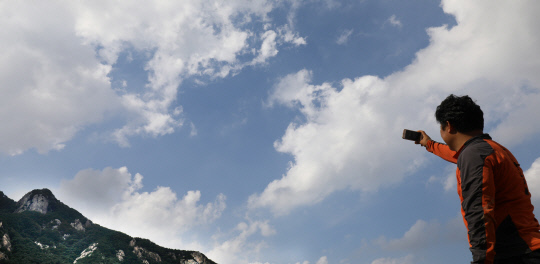 뭉게구름사이로 파란하늘이 펼쳐진 13일 오후 계룡산국립공원을 찾은 한 시민이 휴대폰으로 풍경을 담고 있다. 신호철 기자
