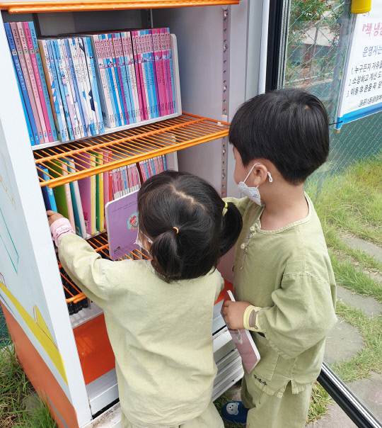 서산시 온석저수지 공원에 위치한 `제1호 책 냉장고`에서 아이들이 읽을 책을 고르고 있다. 사진=동문1동 제공
