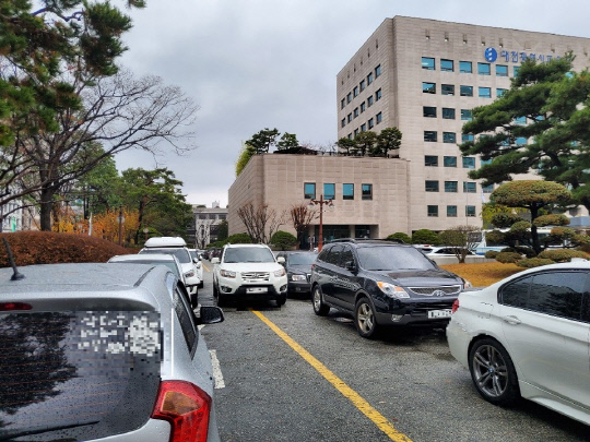 19일 대전시교육청사 도로 양쪽마다 이면 주차가 빼곡히 돼있는 가운데 한 차량이 위태롭게 주차장을 빠져나오고 있다. 사진=박우경 기자
