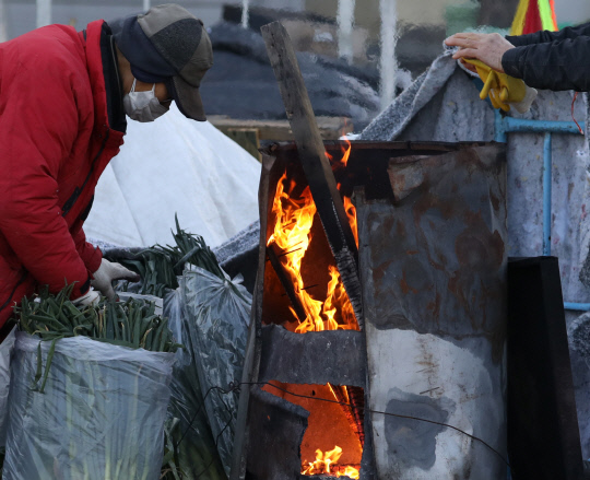 매서운 칼바람과 함께 강추위가 이어진 15일 오전 대전 한 농산물시장에서 상인들이 불을 쬐며 몸을 녹이고 있다. 신호철 기자
