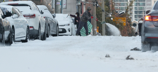 강력한 북극 한파와 함께 눈이 내린 7일 오전 대전 서구 한 주택가 이면도로에서 시민들이 주차된 차량에 눈을 치우고 있다. 신호철 기자
