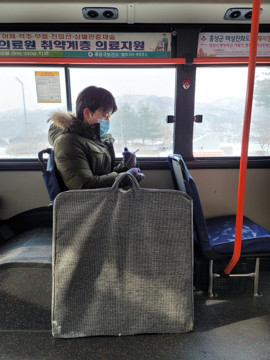 기자가 `ㄷ`자형 휴대용 비말차단기를 갖고 내포신도시에서 버스를 탑승한 모습.
