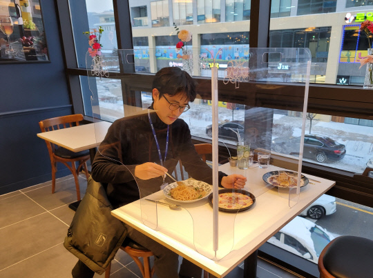 기자가 내포신도시의 한 식당에 `ㄷ`자형 휴대용 비말차단기를 설치하고 식사하는 모습.
