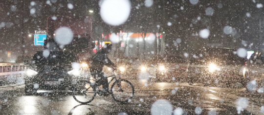 중부지방을 중심으로 눈이 내린 12일 저녁 대전 유성구 구암역 인근 교차로에서 한 시민이 자전거를 타고 조심스럽게 귀가하고 있다. 신호철 기자
