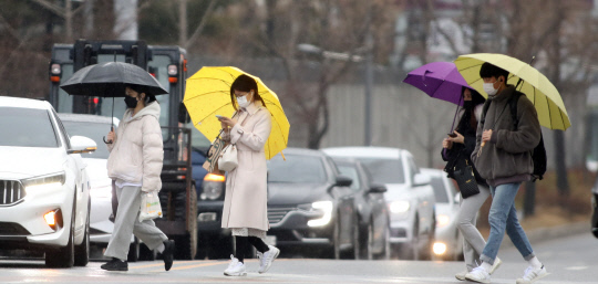 봄을 재촉하는 비가 내린 26일 대전 유성구 충남대학교 앞에서 시민들이 우산을 쓰고 횡단보도를 건너고 있다. 신호철 기자
