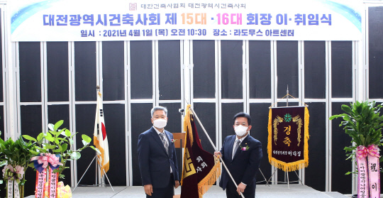1일 대전시건축사회 제15대·제16대 회장 이취임식에서 김용각(오른쪽) 전 회장이 박태식 신임 회장에게 협회기를 전달하고 있다. 사진=대전시건축사회 제공

