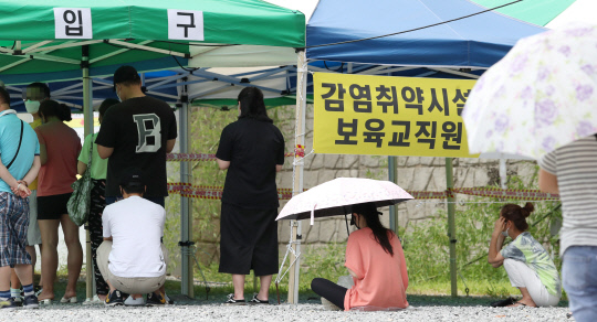 전국적으로 폭염특보가 내려진 25일 대전 서구 엑스포과학공원에 마련된 임시선별진료소를 찾은 시민들이 앉아서 검사 순서를 기다리고 있다. 신호철 기자
