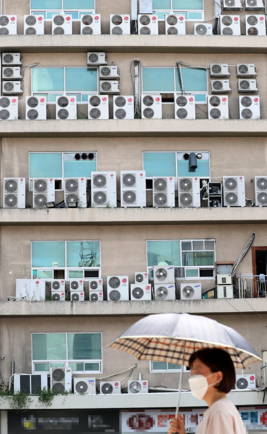 전국 대부분 지역에 폭염 경보가 내려진 4일 대전 서구 한 건물 외벽에 설치된 에어컨 실외기 앞으로 시민이 지나고 있다. 신호철 기자
