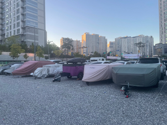 지난 24일 천안 불당동 임시공영주차장에 방수포를 덮은 캠핑 트레일러들이 줄지어 주차돼 있다. 사진=박하늘 기자
